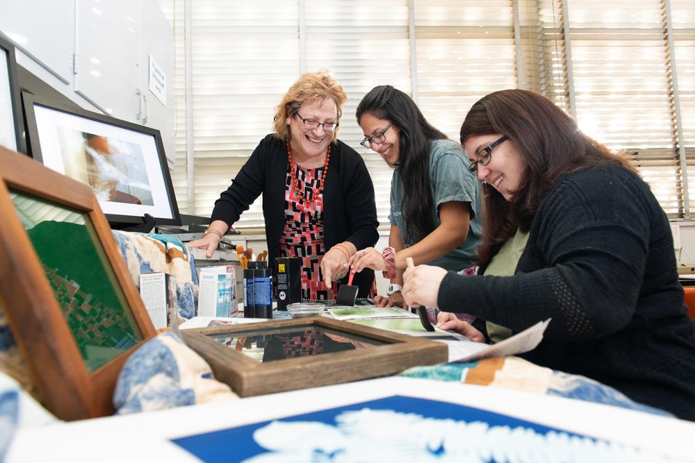 Professor Sheridan in the classroom teaching Alternative Processes photography students how to coat Cyanotype for Sun Prints.